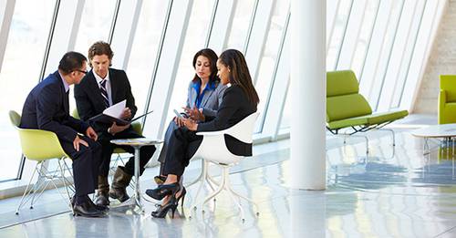 Four people having a meeting around a small table in an office common area